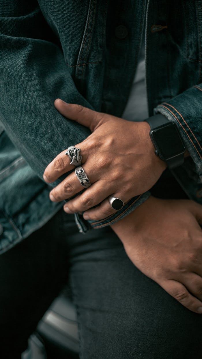 Detailed close-up of hands wearing rings and a smartwatch, showcasing style and technology.