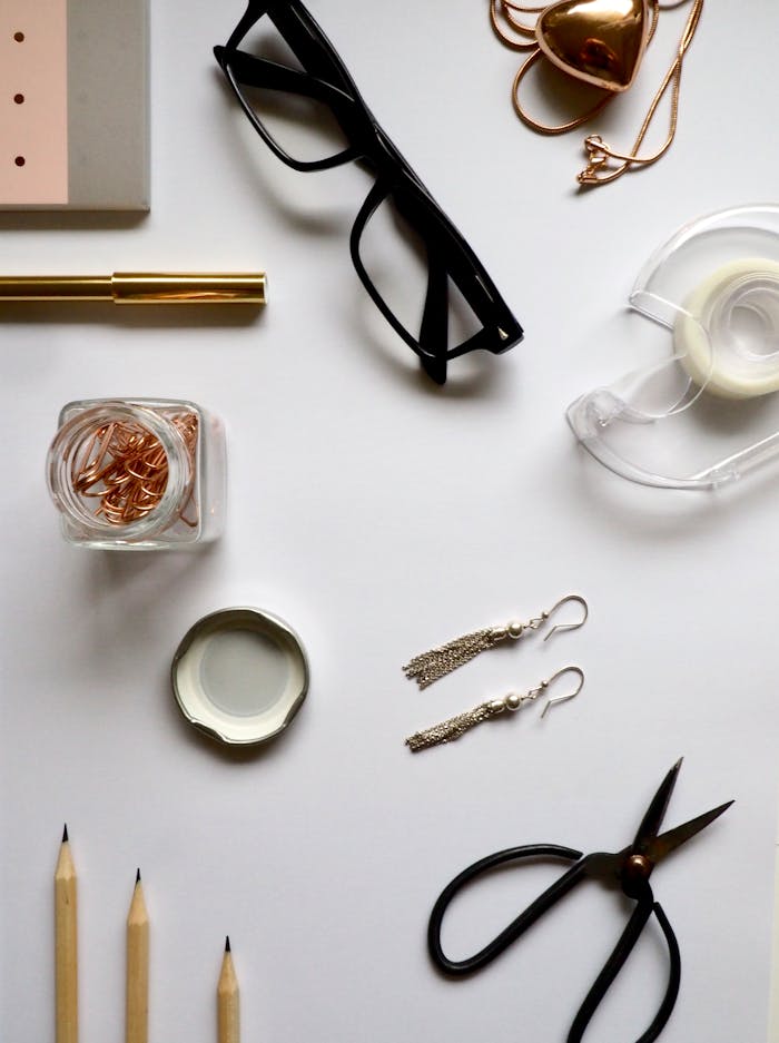 Flat lay of office essentials including eyewear, stationery, and accessories on a desk.